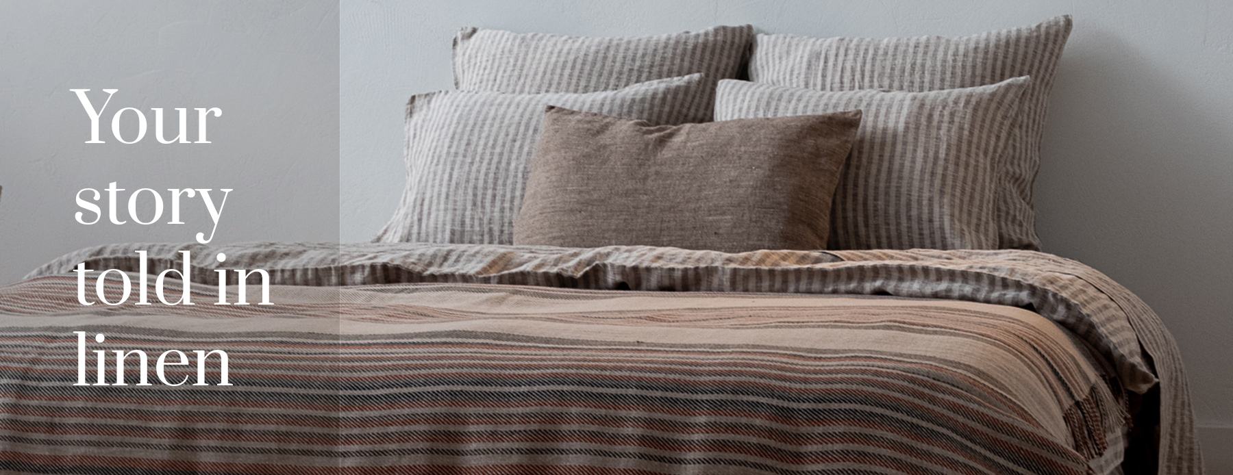 Your story told in linen — natural striped linen bedding and layered pillows.