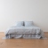 Blue Ticking Stripe linen bedding on a low bed, full view